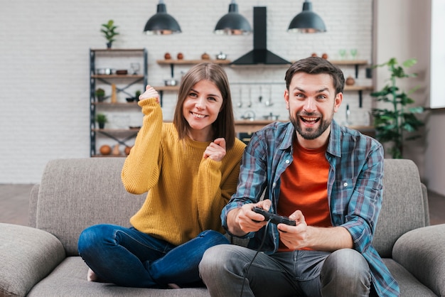 Cheering young couple sitting on sofa playing the video game