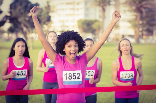 Cheering young woman winning breast cancer marathon