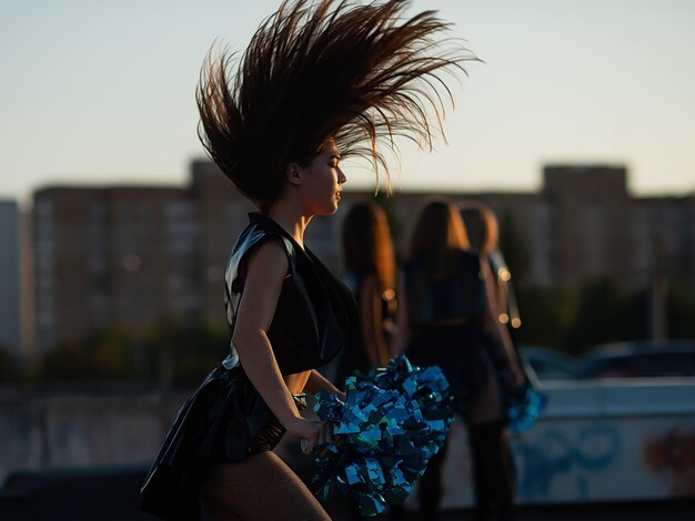 Photo cheerleaders dancing on the roof at sunset against the city landscape