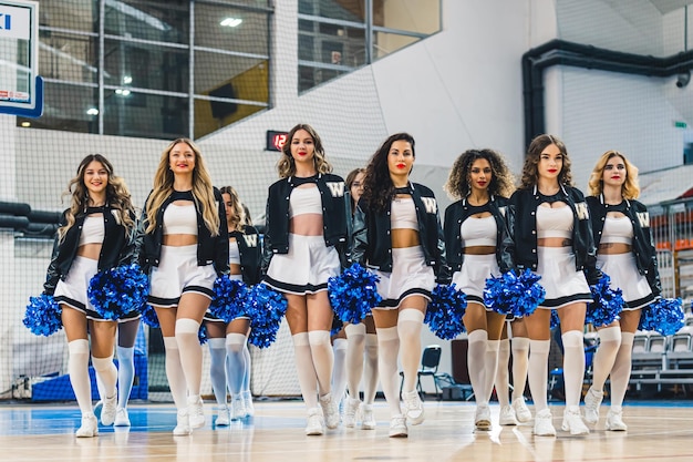 Cheerleaders in minirokjes en kniekousen met pompons die teamgeest tonen