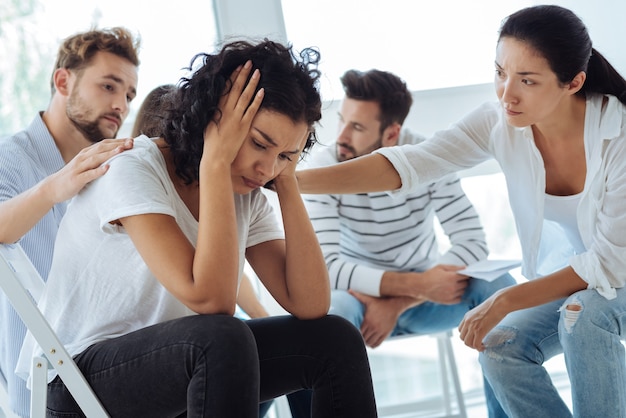 Cheerless unhappy sad woman holding her head and crying while feeling very upset