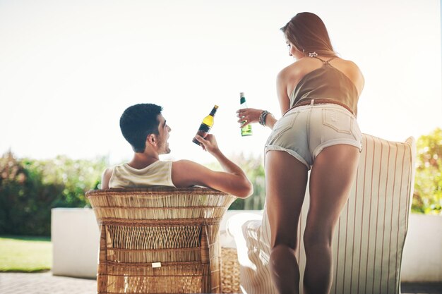 Cheers babe Rearview shot of an affectionate young couple cheersing while drinking beer on their patio