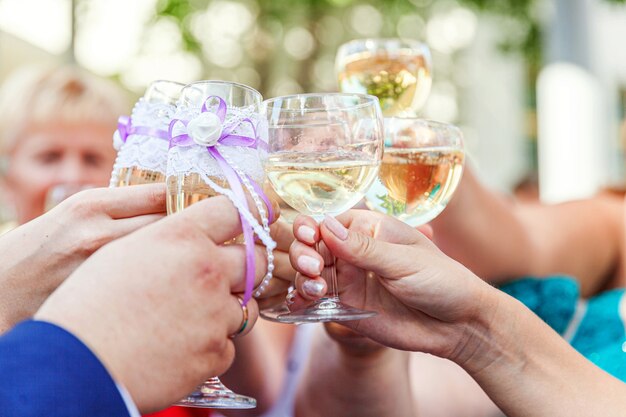 Cheers. Group of people drinking and toasting in restaurant. Hands holding glasses of champagne and wine making toast. Christmas new year wedding holiday party time. Celebration and nightlife concept.