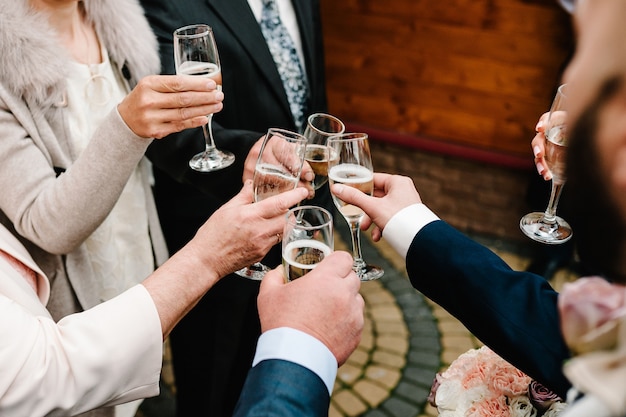 Cheers! People celebrate and raise glasses of wine for toast. Group of man and woman cheering with champagne.