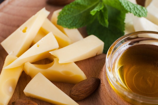 Сыр миндаль и миска с медом крупным планом Натуральные органические закуски домашние продукты