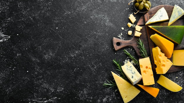 검은 돌 배경 위에 있는 치즈와 스낵의 치즈 구색 위쪽 보기 텍스트를 위한 여유 공간