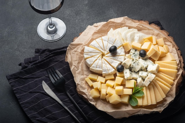 Cheese assortment on plate with red wine on a dark background