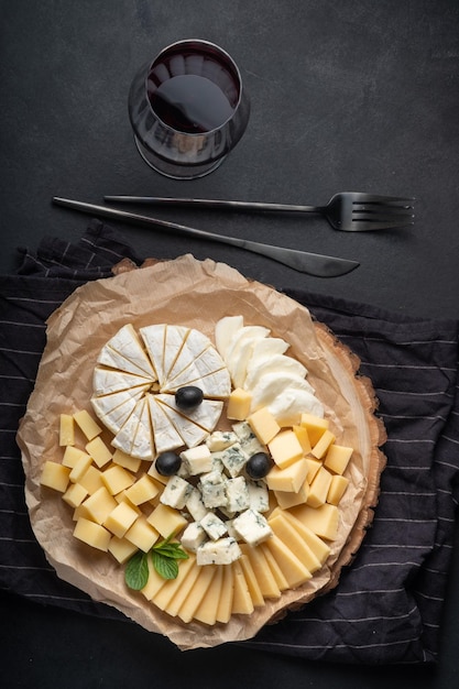 Foto assortimento di formaggi su piatto con vino rosso su sfondo scuro