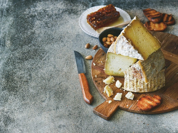 Cheese assortment and snacks on rustic wooden board copy space