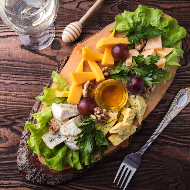 Cheese assortment on wooden board  grape and nuts. closeup. top view