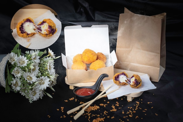 Cheese ball in paper container, hot, smoked, black background