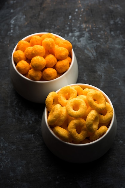 Cheese balls rings, Corn Puff with crispy salty Wheel fryums. Served in a white plate or wooden bowl. Selective focus