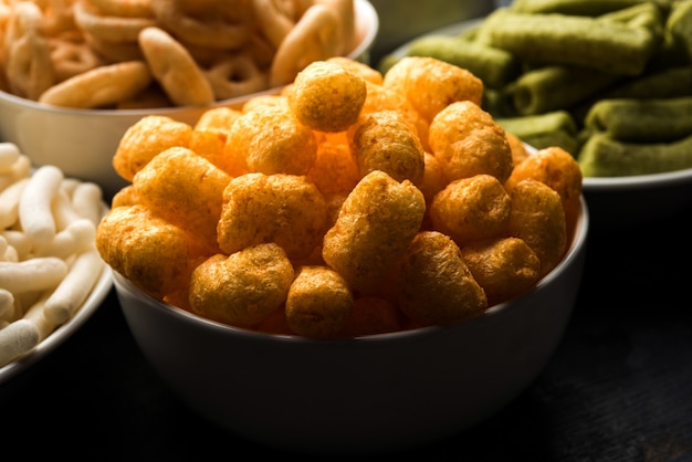 Cheese balls, rings, Corn or wheat Puff with crispy salty Wheel fryums. Served in a white plate or wooden bowl. Selective focus