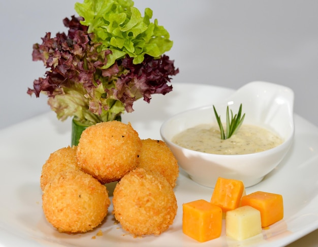 Cheese balls with dip served in a dish isolated on table side view