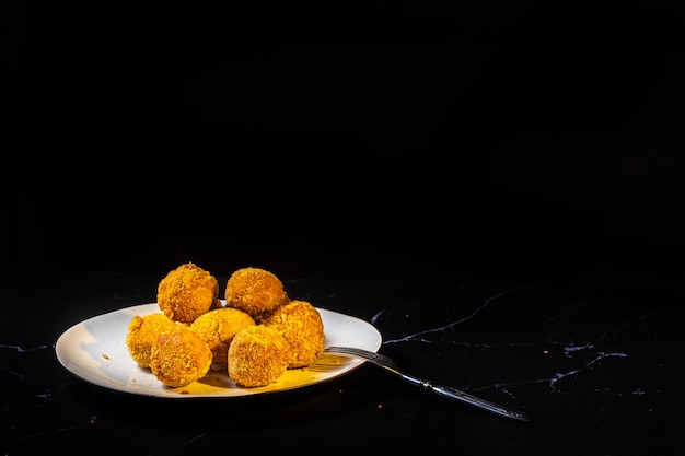 Cheese balls with garlic and dill inside for a snack in a plate on a black background