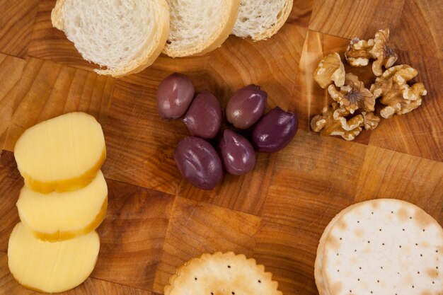 Cheese, bread, olives, biscuits and walnut on wooden board