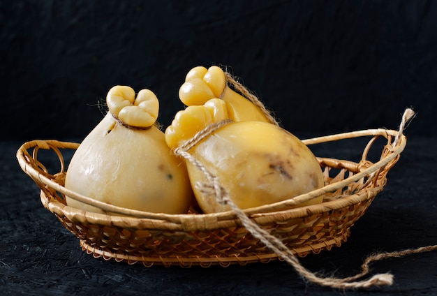 Cheese Caciocavallo in a basket on a black background. Cheese pear