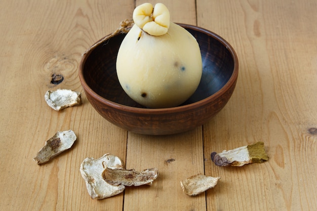 木製の背景に乾燥ポルチーニ茸のチーズCaciocavallo。チーズ梨