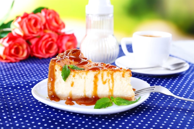 Cheese cake in plate on polka dot tablecloth on nature background