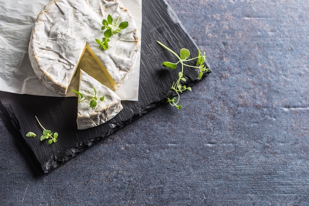 Foto camambert del formaggio dalle erbe dell'origano sul bordo dell'ardesia.