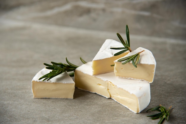 Cheese camembert or brie with rosemary on cutting board on marble stone background. Copy space.  Studio photo.