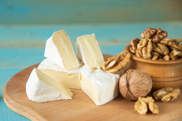 Cheese camembert or brie with walnut kernels on blue wooden background. Copy space.  Studio photo.