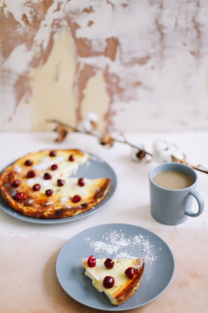 cheese casserole with berries and a cup of coffee on table top view