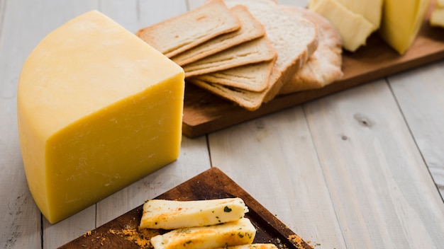 Cheese chunk and bread slices on wooden board over the table