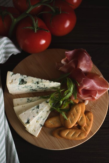 Cheese and cold cuts on a wooden tray on a wooden table