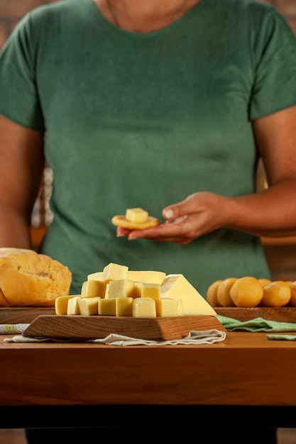 Cheese cubes with woman preparing brazilian croquettes stuffed with cheese in background