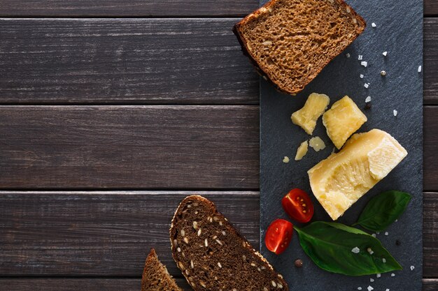 Cheese delikatessen with bread on black stone, parmesan