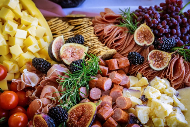 Foto formaggio, fichi, uva e cracker a bordo di salumi.