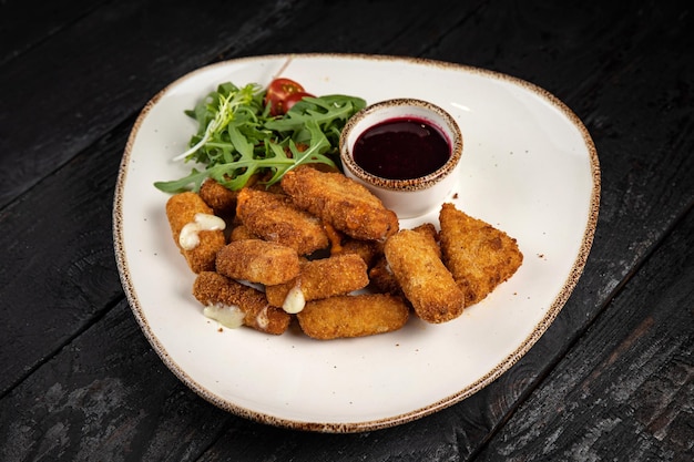 Cheese fries with herbs and sauce on plates on a wooden table