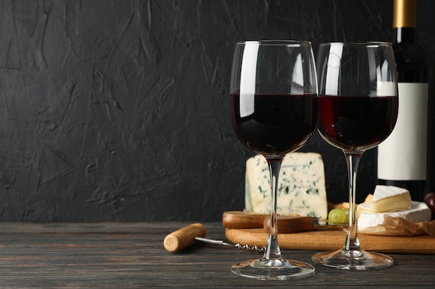 Cheese, grape, bottle and glasses with wine on wooden