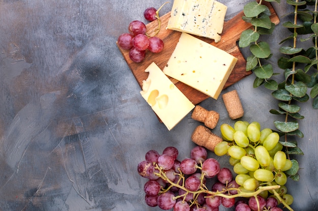 cheese and grapes on a black gray concrete background