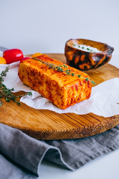 Cheese halumi with smoked paprika on a wooden board with tomatoes, and thyme