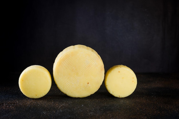 Photo cheese heads of different kinds stacked on dark table