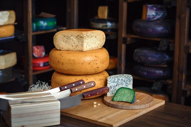 Cheese heads with slices and knives on a wooden board with an interior