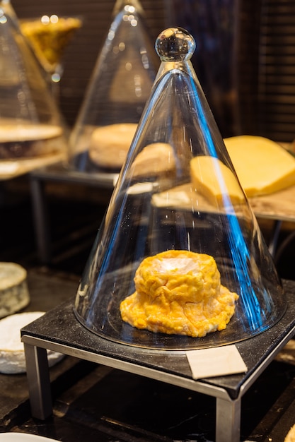 Cheese inside glass cone on black stone plate.