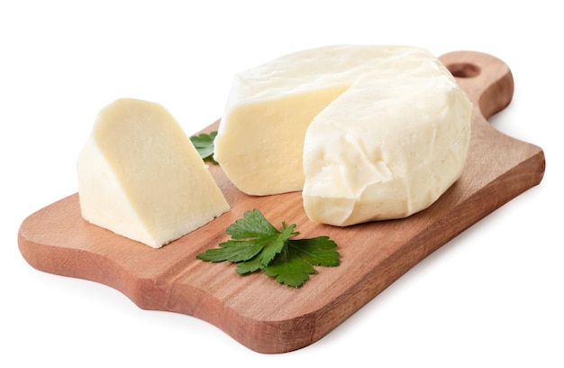 Cheese on a kitchen board with parsley leaves close-up on a white background. Isolated