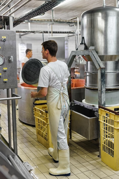Сыродел работает на молочном заводе по производству сыра Грюйер де Конт во Франш-Конте, Бургундия, Франция.