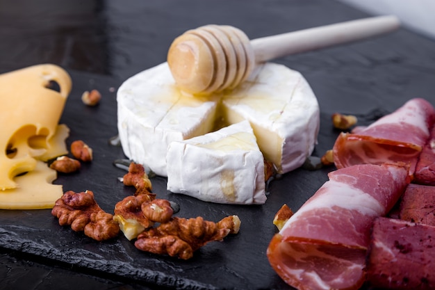 Cheese and meat plate with walnuts on black slate plate surface