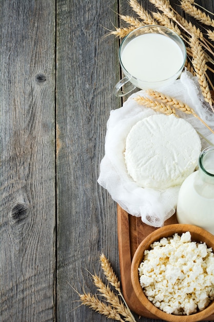 Cheese, milk, cottage cheese and wheat on old wooden