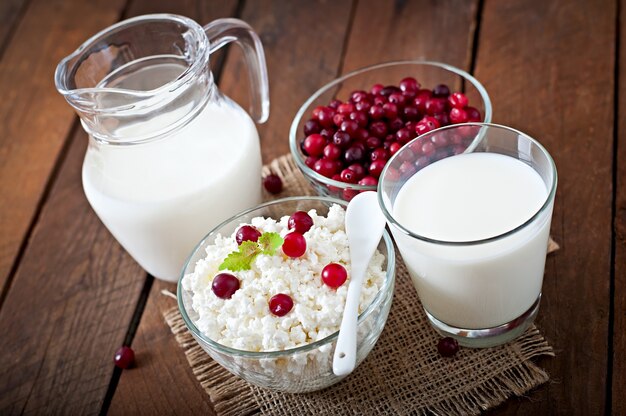 Cheese, milk and cranberries on a wooden table in a rustic style