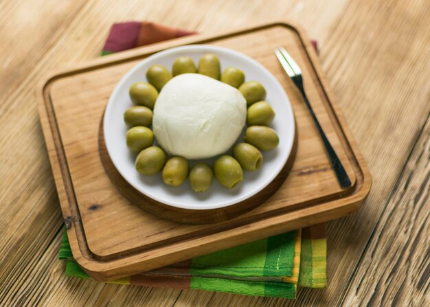 Foto formaggio mozzarella e olive su un piatto su un fondo di legno