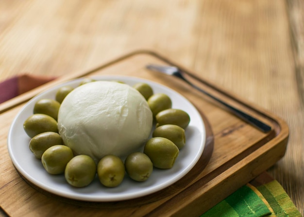 Cheese mozzarella and olives on a plate on a wooden background