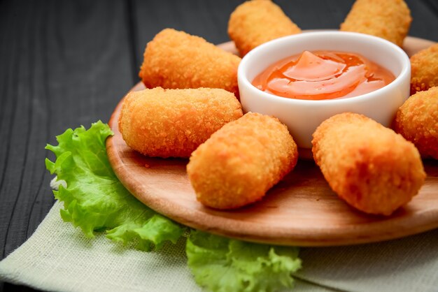 Cheese nuggets with mango fruit sauce on a wooden plate