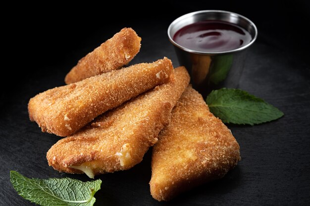 Cheese nuggets with raspberry sauce and mint, on a black background