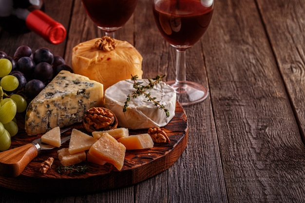 Cheese, nuts, grapes, and red wine on wooden background