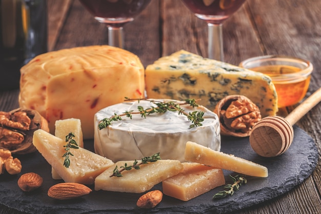 Cheese, nuts, honey and red wine on wooden background